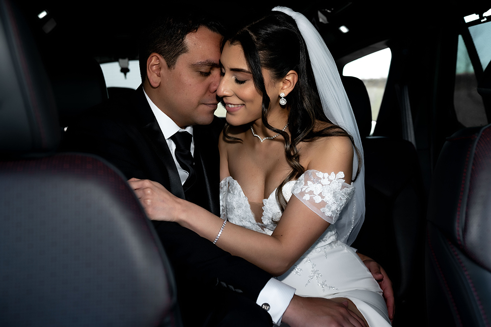 Just married couple holding hands in the backseat