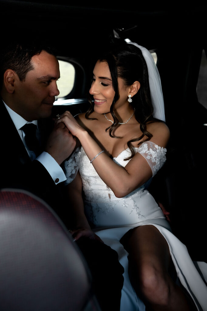 Bride and groom smiling at each other inside the car